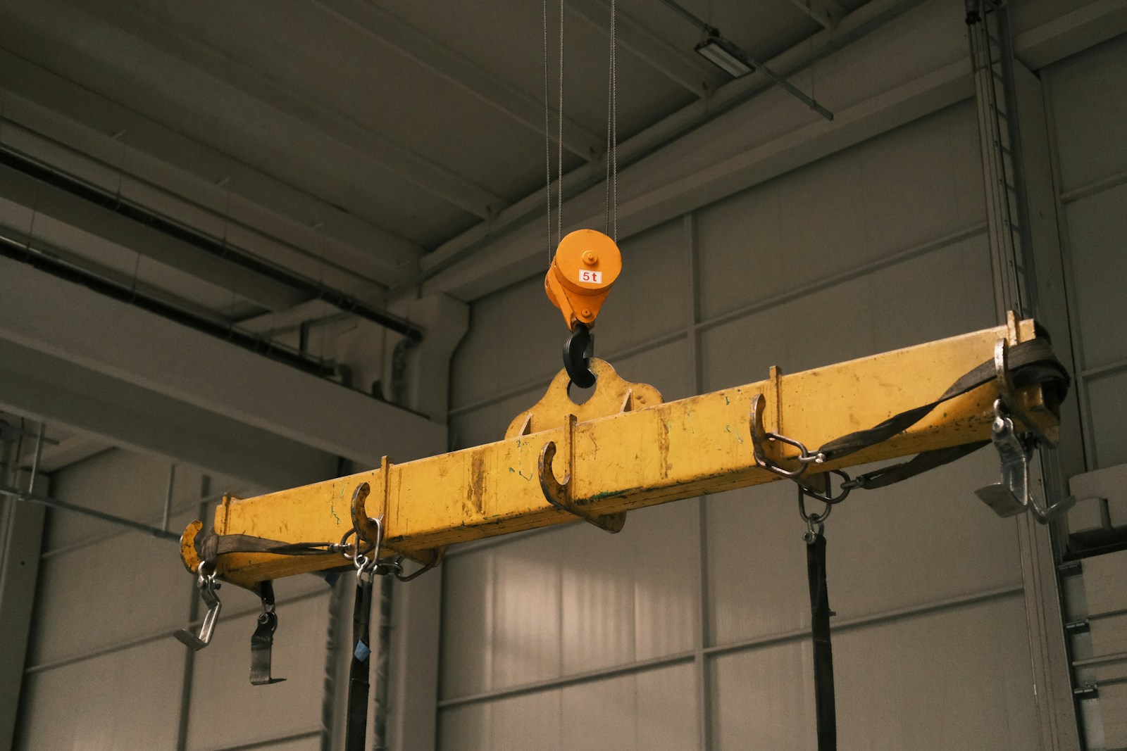 A yellow crane hanging from a ceiling in a garage